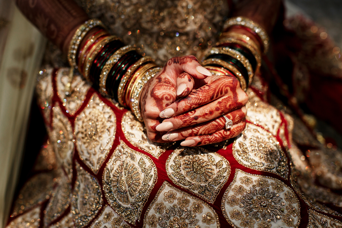 Beautiful mehndi patterns cover bride's fingers which she holds over the lehenga